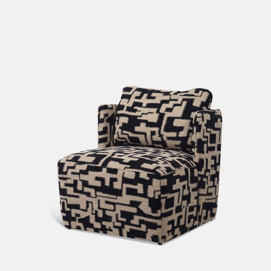 A large boxy patterned armchair, upholstered in an abstract black and brown fabric.