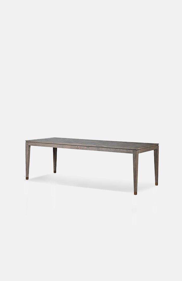 Cutout of the Frances Dining Table, a long rectangular table in oak veneer with a parquet style surface and slim tapered legs