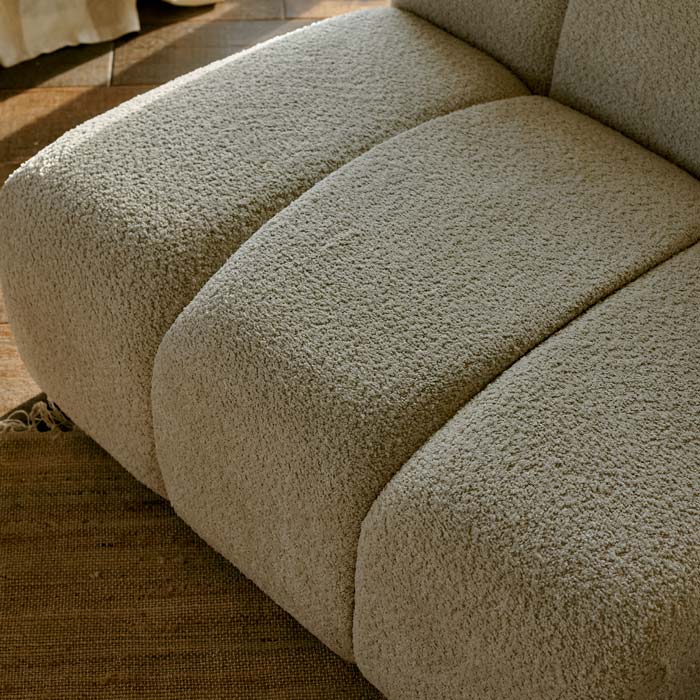 Close image of the fabric of an armless, panelled cream occasional chair