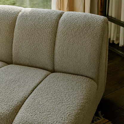 Detail of the fabric of an armless cream accent chair.