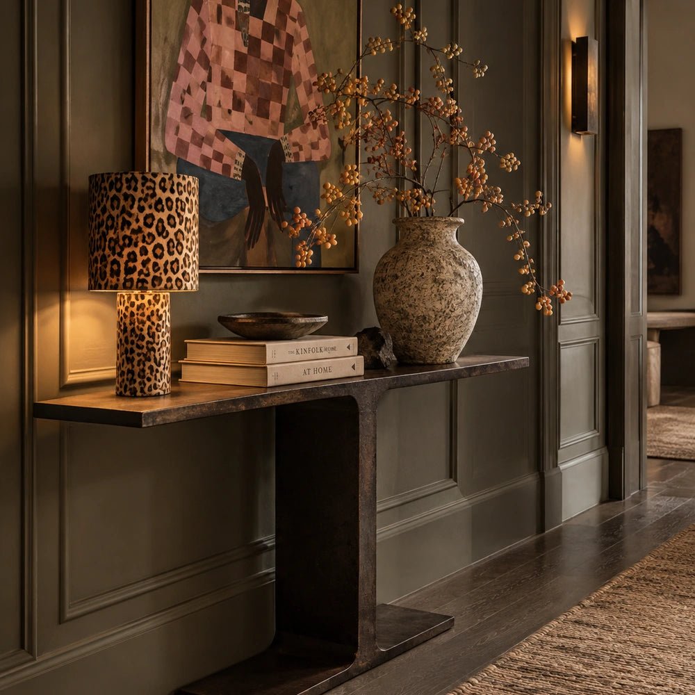 Harrow Console with dark open frame and shelves, styled with a table lamp, ceramics and artwork against a softly textured neutral wall.