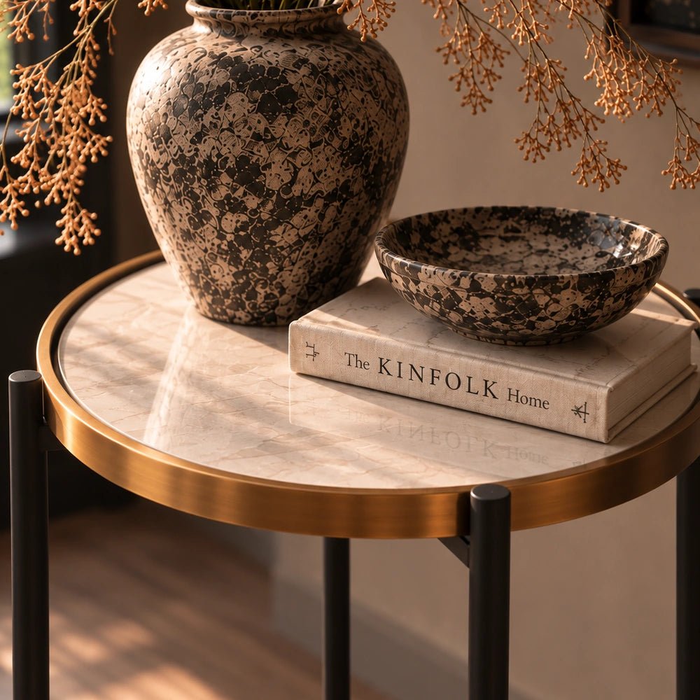 Huxton Side Table with rounded dark top and sculptural base, styled beside a neutral sofa with decorative objects in a warm contemporary living room.