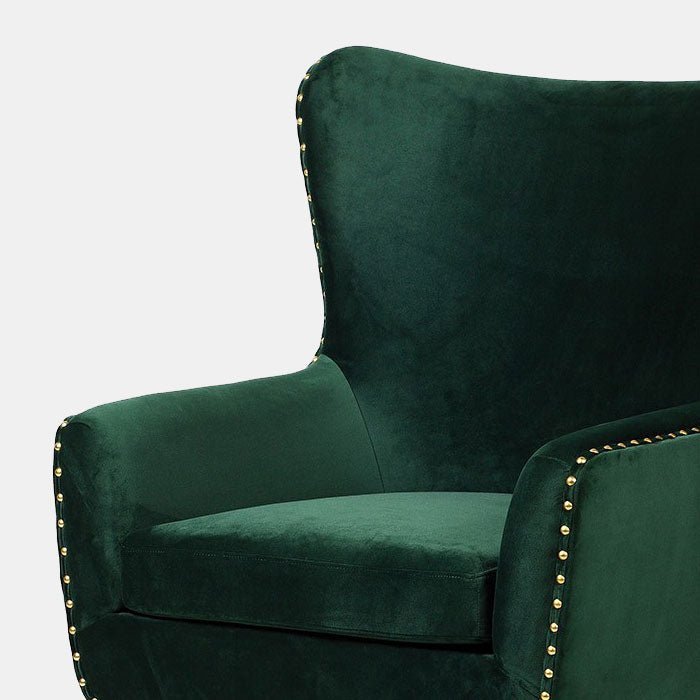 The Jermyn Chair, a stylish club chair with a sleek curved back, gold studding and gold tipped legs in deep green velvet.
