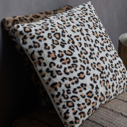 A leopard print furry cushion, in white, orange and black colours.
