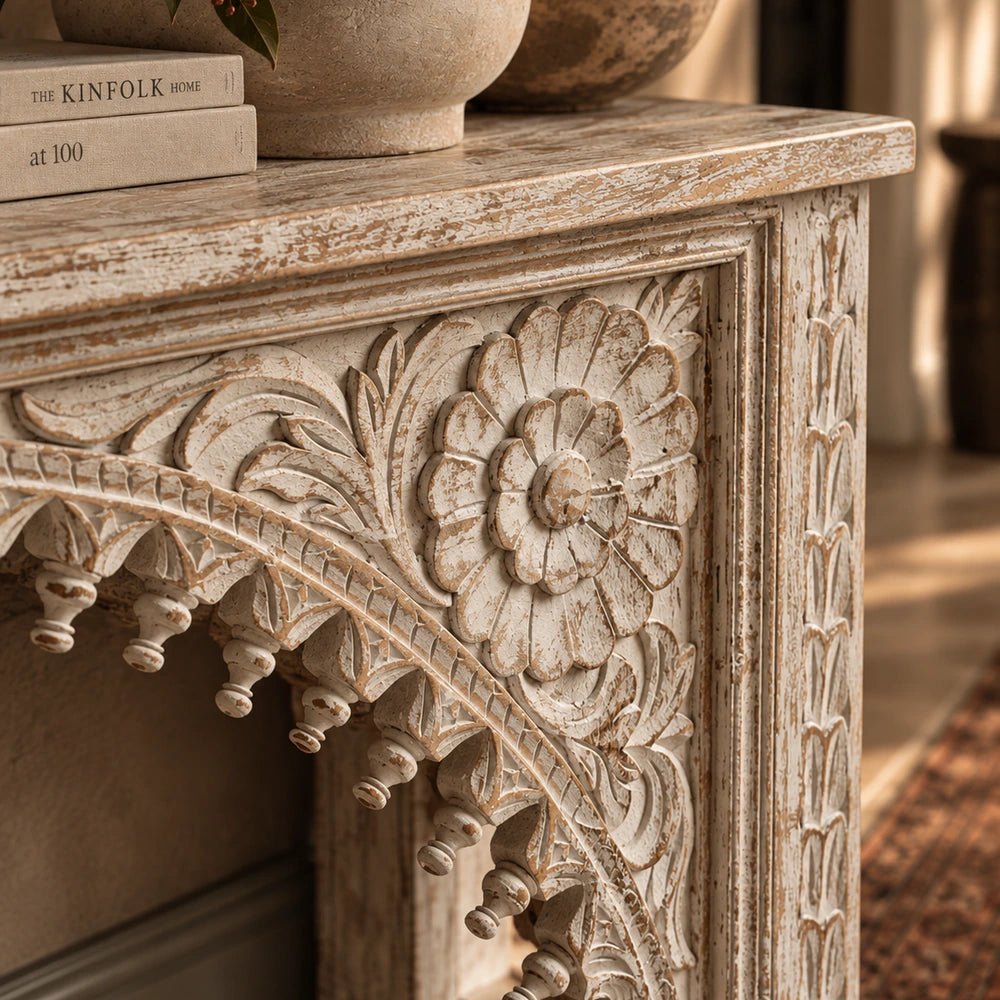 Karnata Carved Console with detailed carved front and dark finish, styled beneath large artwork with lamps and decorative objects in a warm interior.