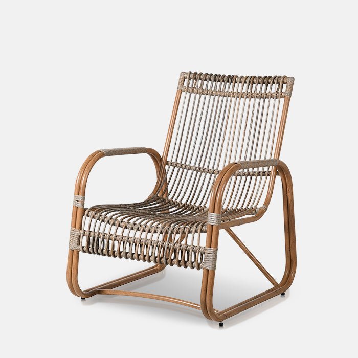 The Kemble Rattan Occasional Chair, a tall curvy rattan armchair with square arms and a boho feel.