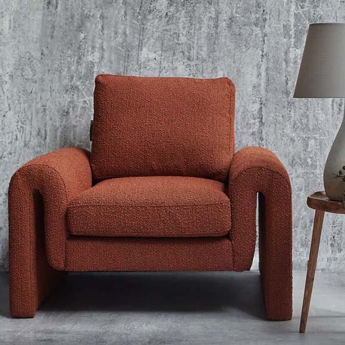 Abigail Ahern Manhattan Boucle Armchair in rich rust and sienna-toned boucle upholstery, featuring a large sculptural silhouette with softly curved sides, styled as a striking statement chair in a sophisticated modern interior.