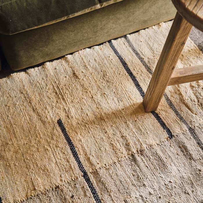 Detail of a cream woven rough textured rug with navy lines