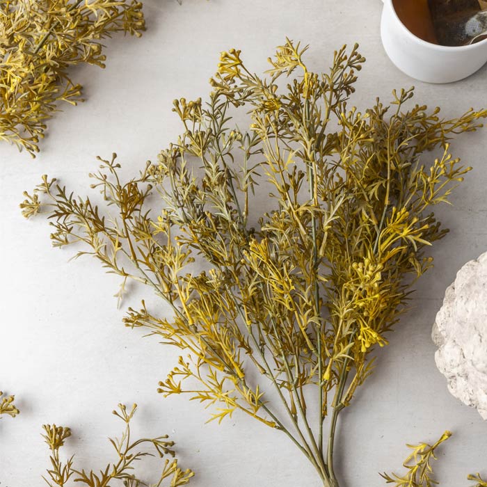 A single stem of faux meadow grass flaxen in a warm yellow colour.