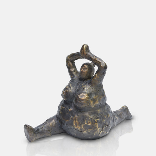 A cutout of an aged bronze-look resin sculpture of female in splits yoga pose.