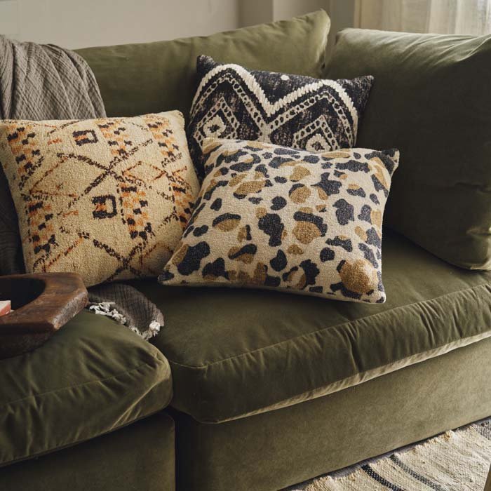 A set of 3 cushions styled on a green velvet sofa. Cushions with vintage style patterns styled together for a chic look to your sofa or accent chair.