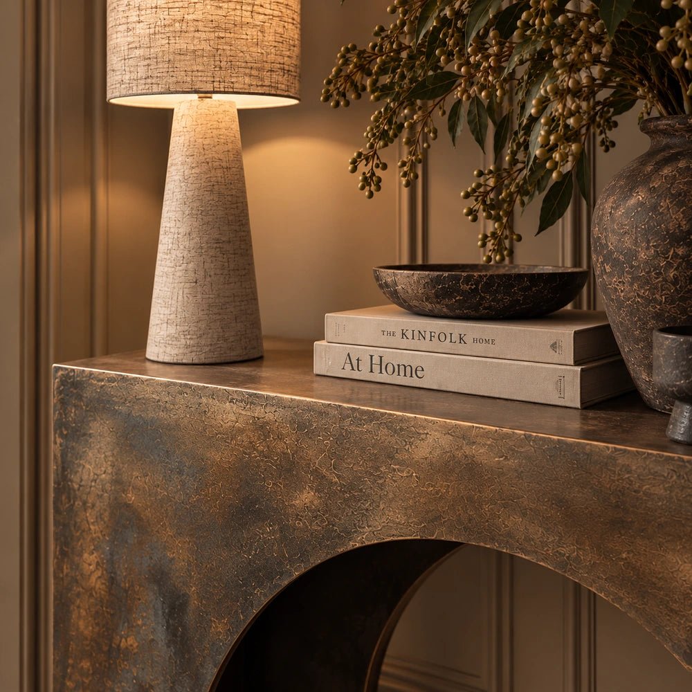 Orcheston Metal Console Table styled in a warm neutral interior, with its slim burnished metal frame displayed alongside sculptural accessories and layered decorative objects.