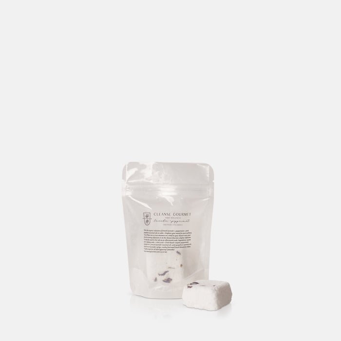 A single white Lavender and Peppermint Shower Steamer, placed in front of its translucent packaging.