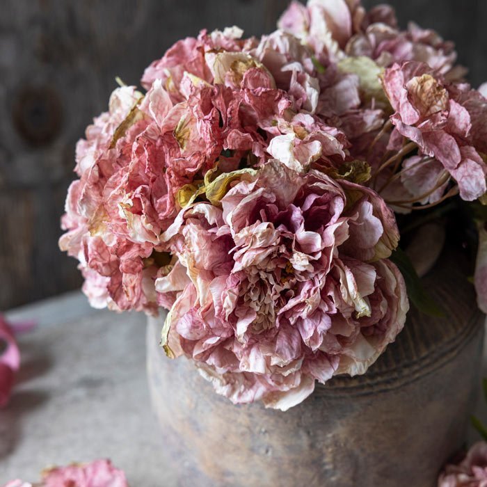 Faux pink hydrangeas in a floral arrangement in a grey stone vase.