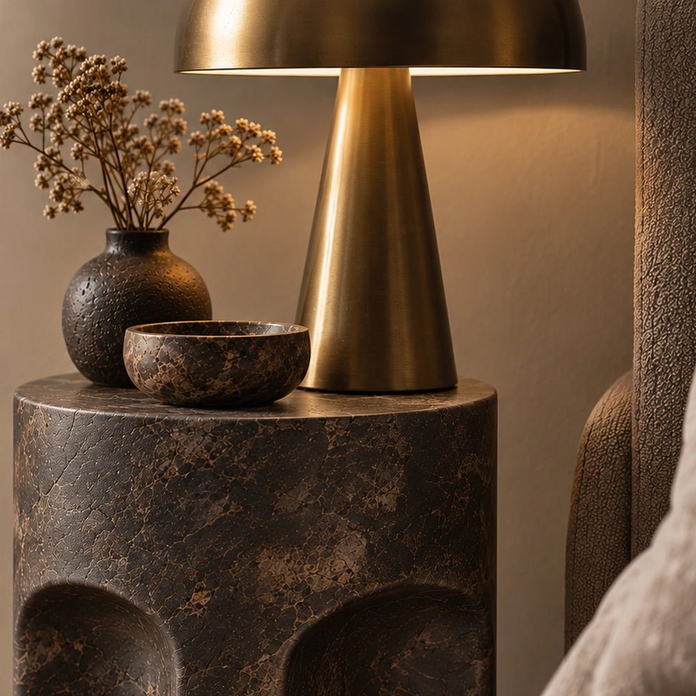 Pinch Round Side Table styled beside a cream sofa with a glowing table lamp, dark ceramic vase and layered neutral contemporary living room furnishings.