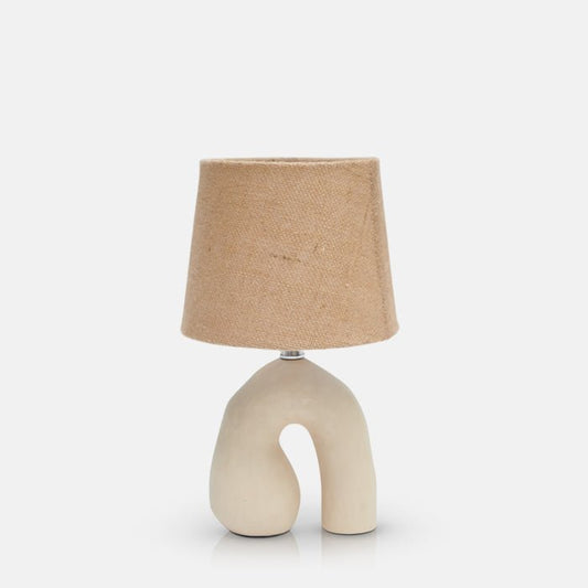 Small table lamp with cream sculptural ceramic base in shape of upside-down 'U' and natural jute shade.