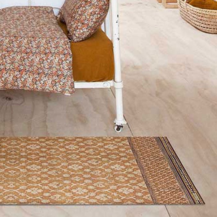 Orange and beige vinyl rug in floral design.