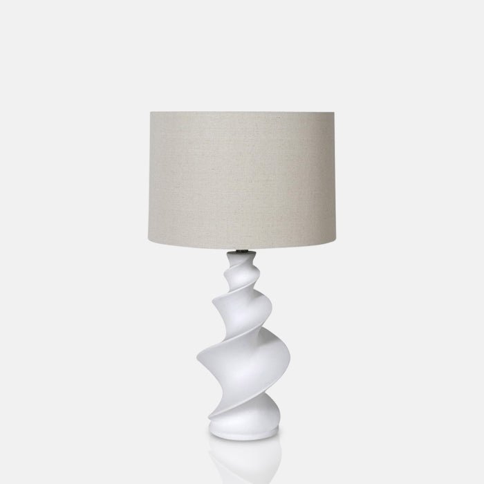 A closeup of the Reo Table Lamp, a white lamp with a spiral white base and a cream drum shade.