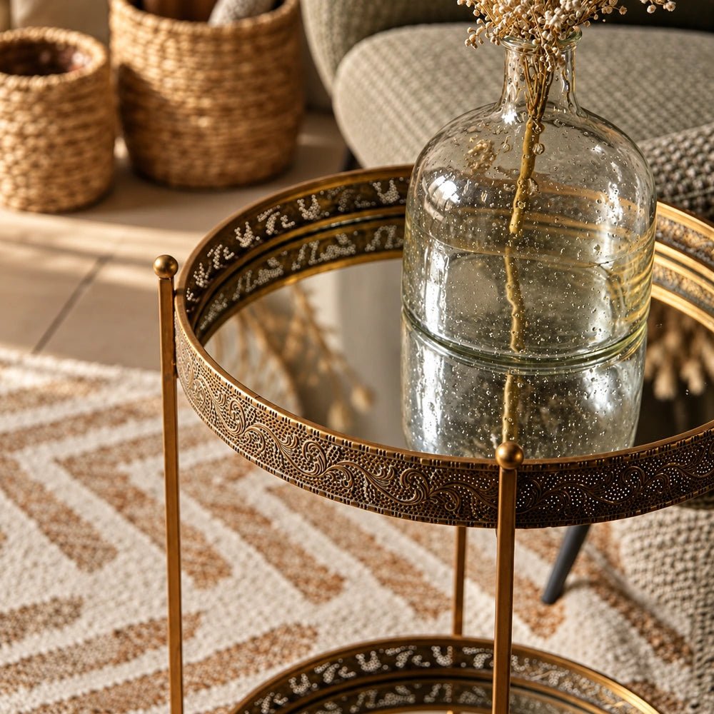 Ritson Mirrored Side Table with ornate antique brass frame and two circular mirrored tiers, styled with a clear glass vase in a neutral living room.