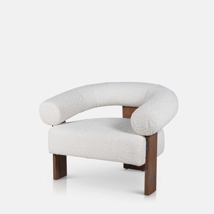 Abigail Ahern Ryton Cream Boucle Armchair in cream textured boucle, featuring a curved mid-century inspired silhouette, generously cushioned seat and distinctive cylindrical armrest and backrest.