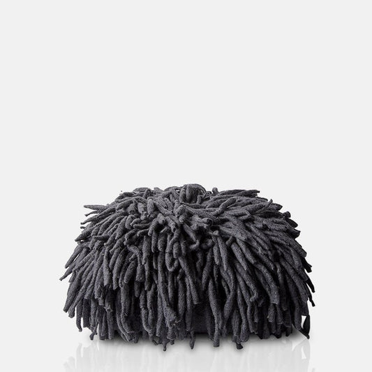A charcoal grey floor pouffe covered in long tendrils of wool.