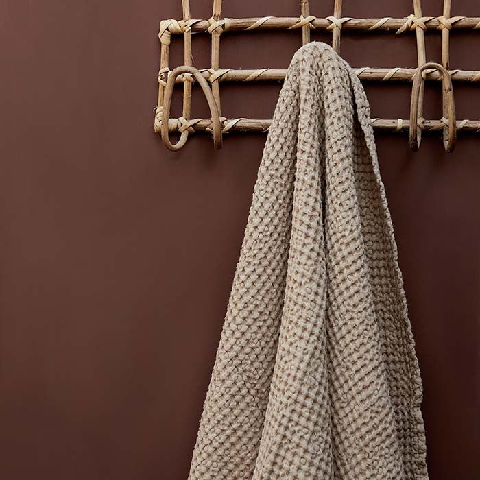 Wooden coat rack hung on a rich red-brown painted wall
