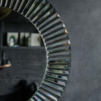 Ribbed mirrored glass frame on a large round mirror hung on a grey wall
