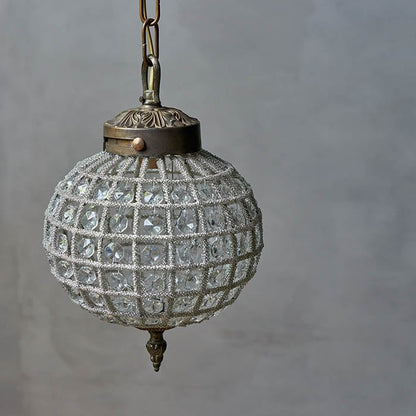 A round bodied clear glass beaded chandelier with bronzed metal details.