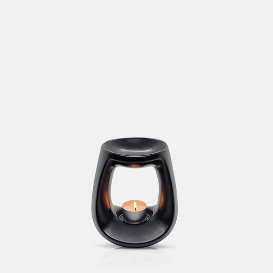 Curvy black ceramic oil burner with a lit tea light in its base