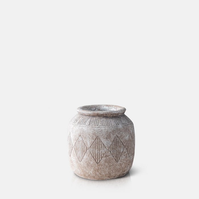 Cutout image on a white background of a pale brown, curved cement vase with a linear diamond pattern engraved on it.