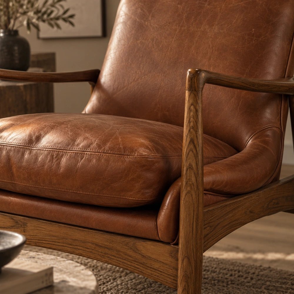 Truman Brown Leather Armchair shown close up with softly creased leather cushions, rounded wooden arms and visible timber frame detailing in warm natural tones.