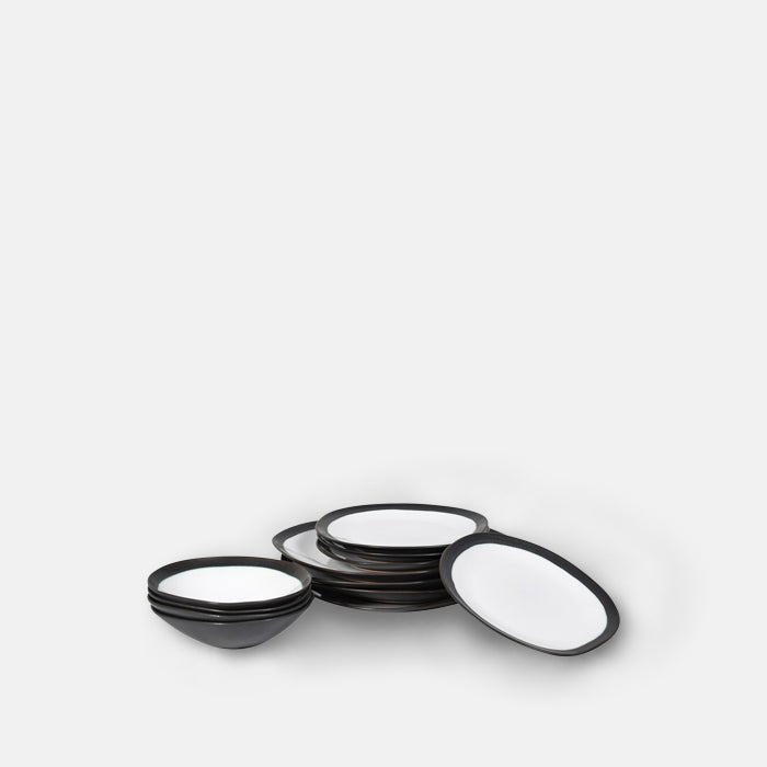 A cutout of the Truman Stoneware Dinner Set - 12 Piece. A set of white organic shaped tableware with a stylish black rim.