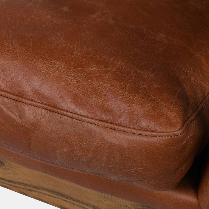 Close-up of the Abigail Ahern Truman Brown Leather Armchair highlighting the rich dark brown leather upholstery, smooth tactile finish and natural detailing of the ash wood frame.