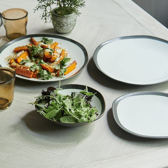 Truman Stoneware Dinner Set - 12 Piece, a set of white and black organic shaped tableware styled with food on a wooden table.