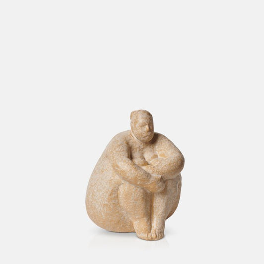 Sitting female sculpture with her arms wrapped around her legs in a thoughtful pose with creamy brown finish.