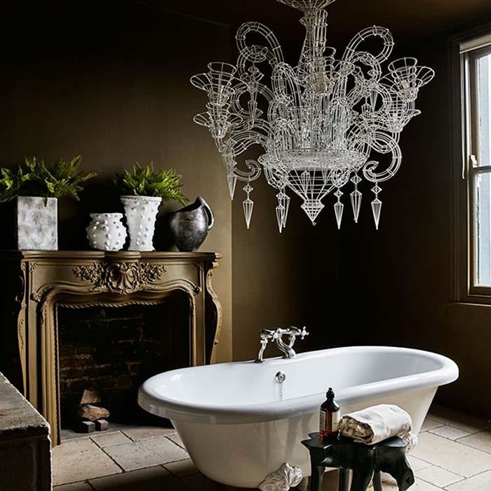 A striking bathroom painted in Wooster Olive paint from Abigail Ahern. Style with large vintage style and a roll top bath chandelier. A dark green paint for your walls and ceiling.