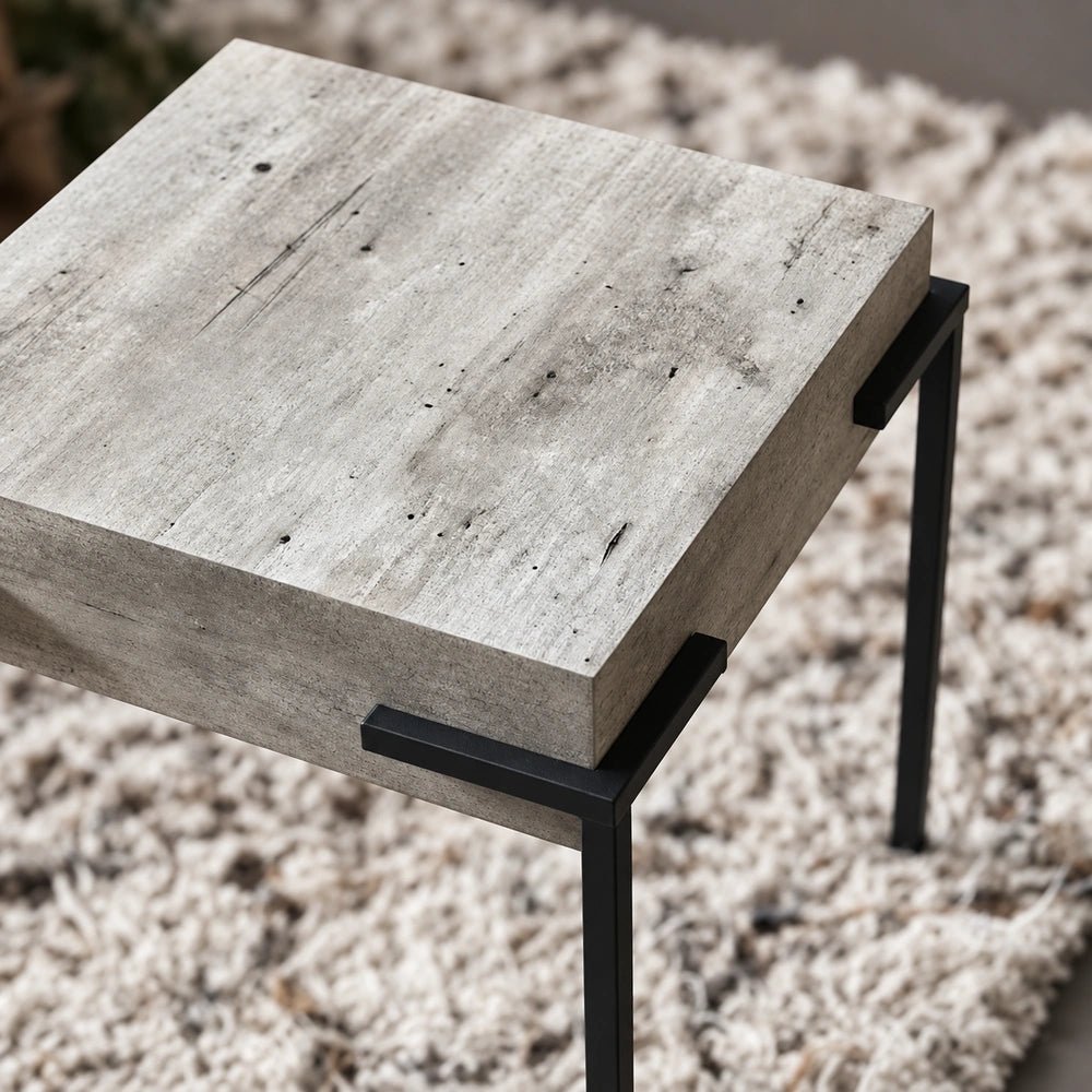 Alberton Faux Concrete Side Table with sculptural grey finish, styled in a warm contemporary living room beside neutral seating and decorative accessories.