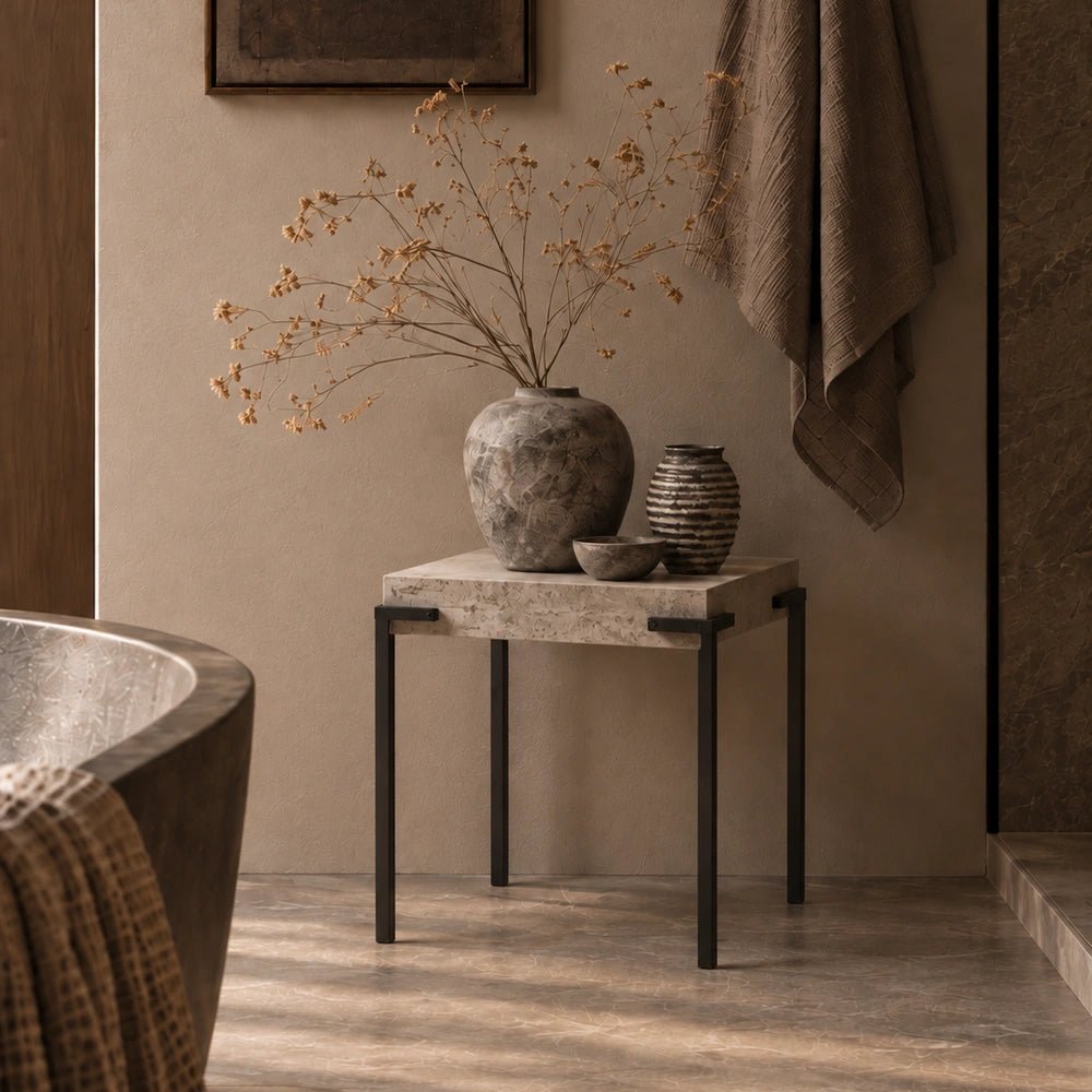 Alberton Faux Concrete Side Table with textured grey surface, styled beside a neutral sofa with warm layered cushions and contemporary decorative objects.