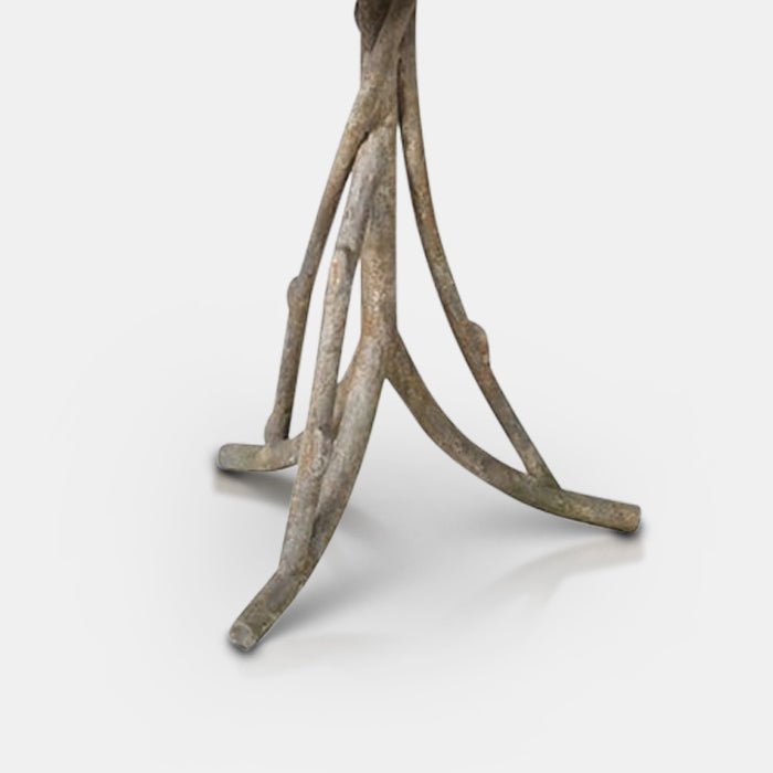 A closeup of the legs of the Alimena Iron Table, curved to resemble tree branches.