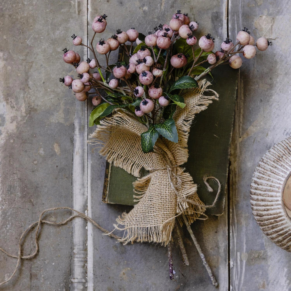 Artificial Crabapple stems arranged as a rustic flat-lay bouquet, showing clusters of blush pink fruit, green leaves and brown stems wrapped in natural hessian.
