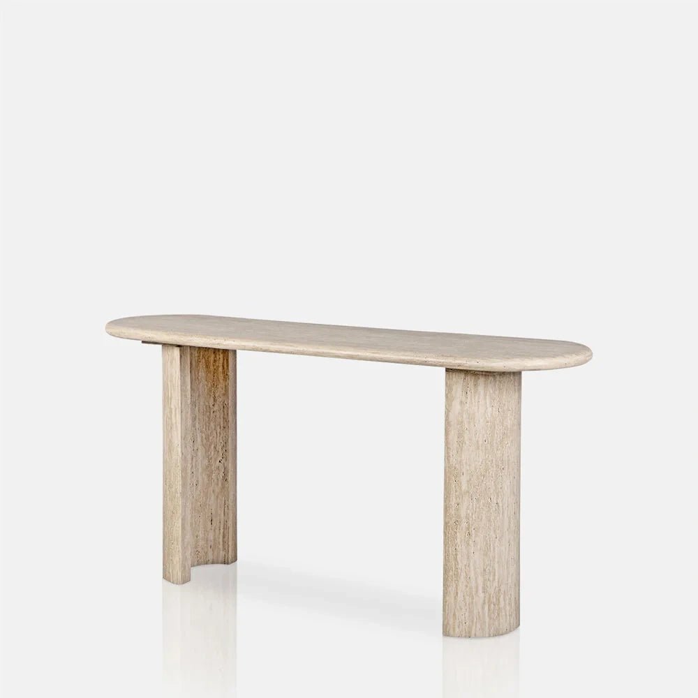 Barnard Travertine Console Table shown at an angle, with a pale beige oval top, two broad legs and visible natural stone markings.