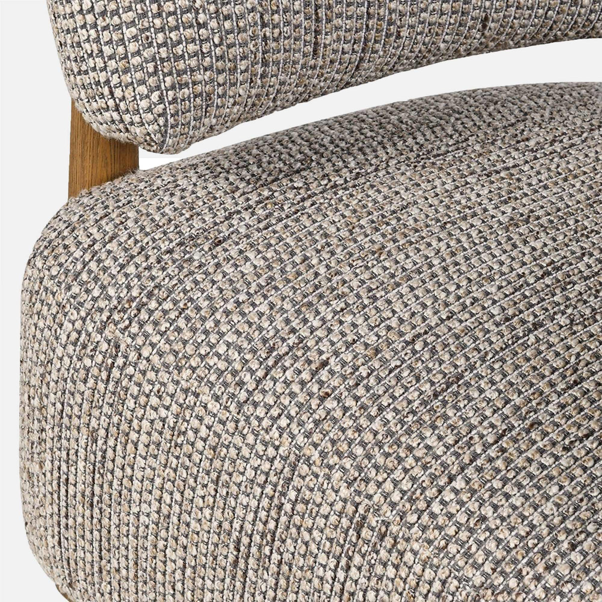 Close-up of the Abigail Ahern Bastian Curved Armchair showing the soft textured neutral upholstery, plush cushioning and gently curved vintage-inspired design.