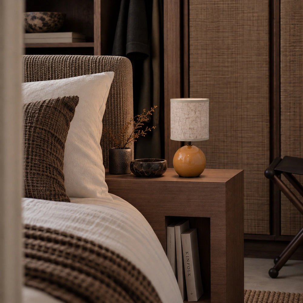 Orange Blair Table Lamp with rounded glossy base and fabric shade styled on a wooden bedside table in a warm neutral bedroom.