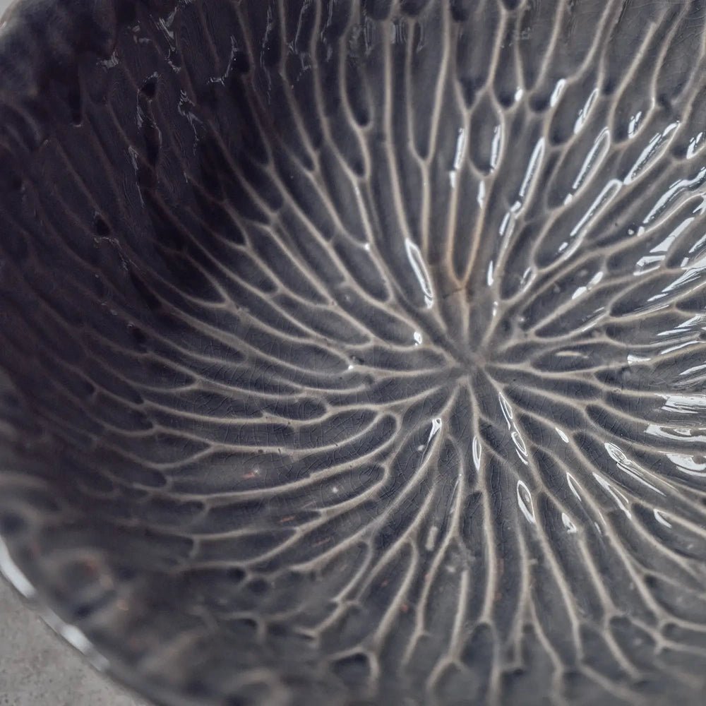 Bowham Ceramic Decorative Bowl showing a dark glazed interior with radiating raised lines and a rippled surface, captured closely to reveal its sculptural texture.