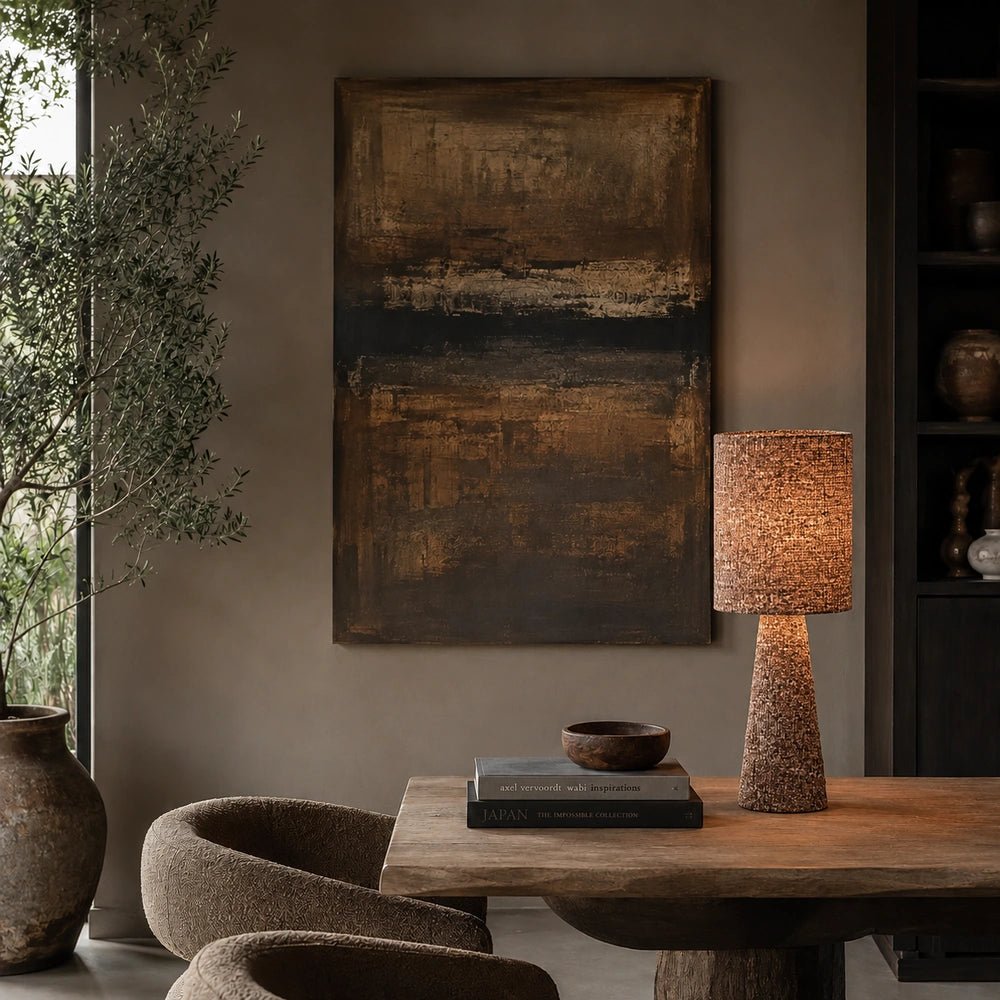 Draycott Boucle Table Lamp with textured boucle shade and tapered base, glowing on a console table against dark artwork in a warm neutral interior.