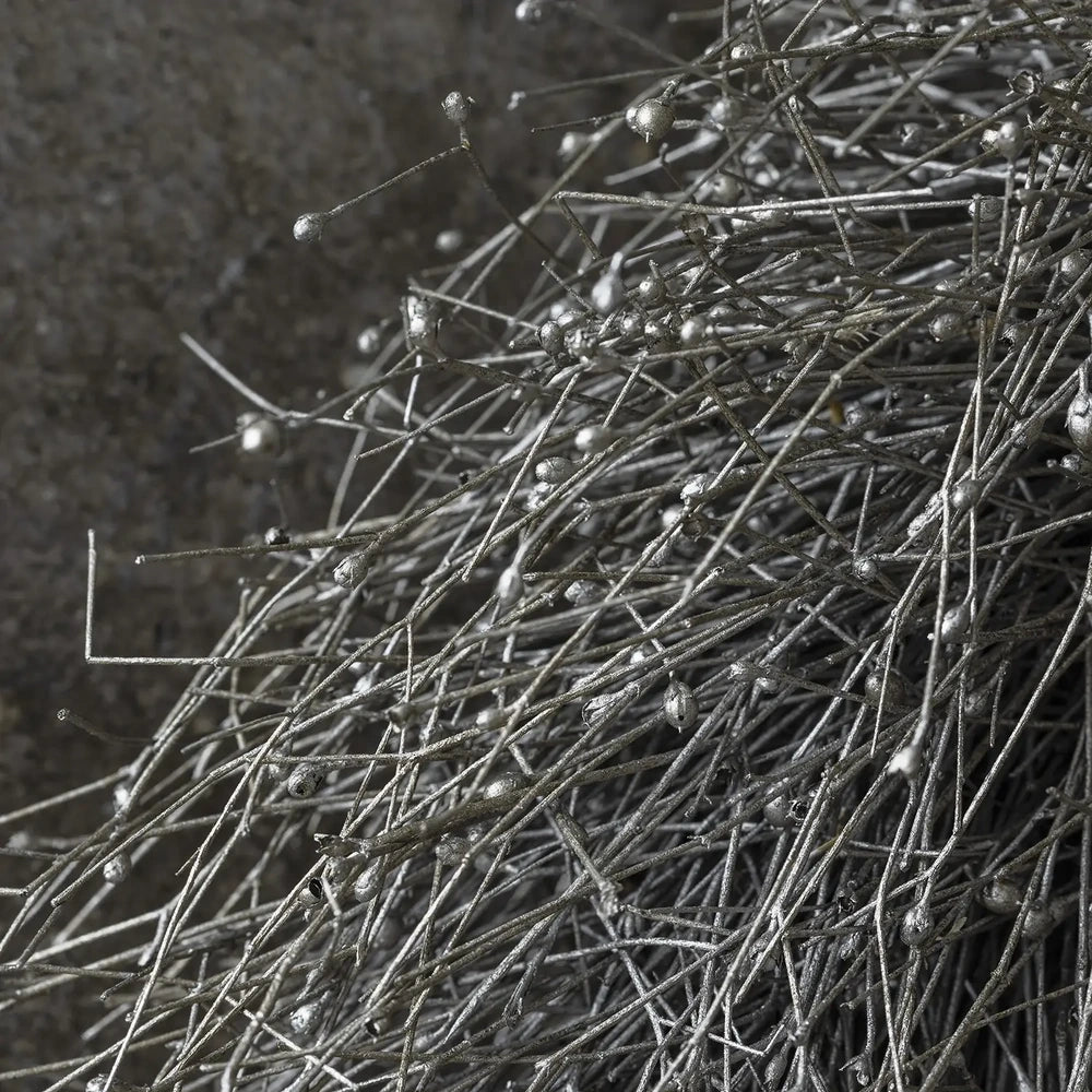 Dried gypsophilia wreath reveals slender interlacing grey stems dotted with tiny pale buds, shown in close detail against a dark softly blurred background.
