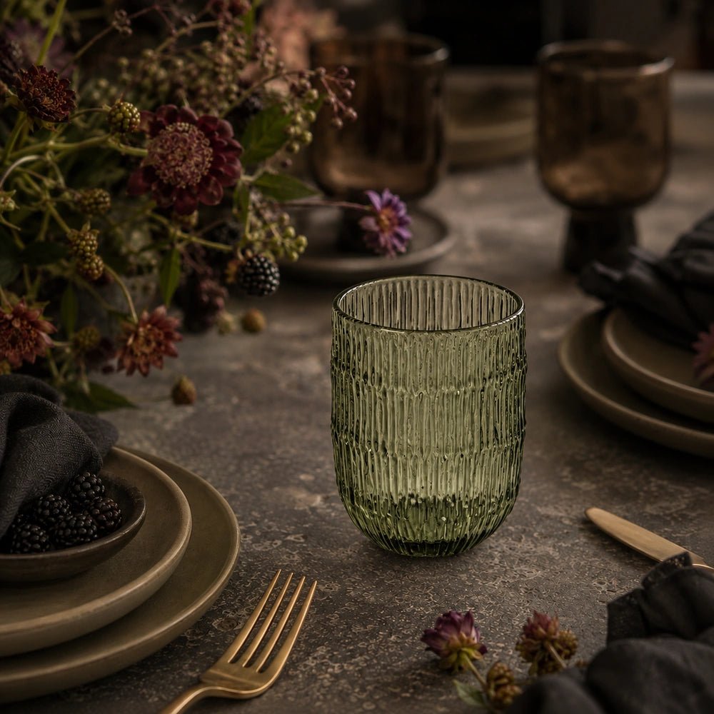 Elden Glass Cup, Green shown as a group of ribbed translucent tumblers on a pale table, styled with neutral linen in soft natural light.