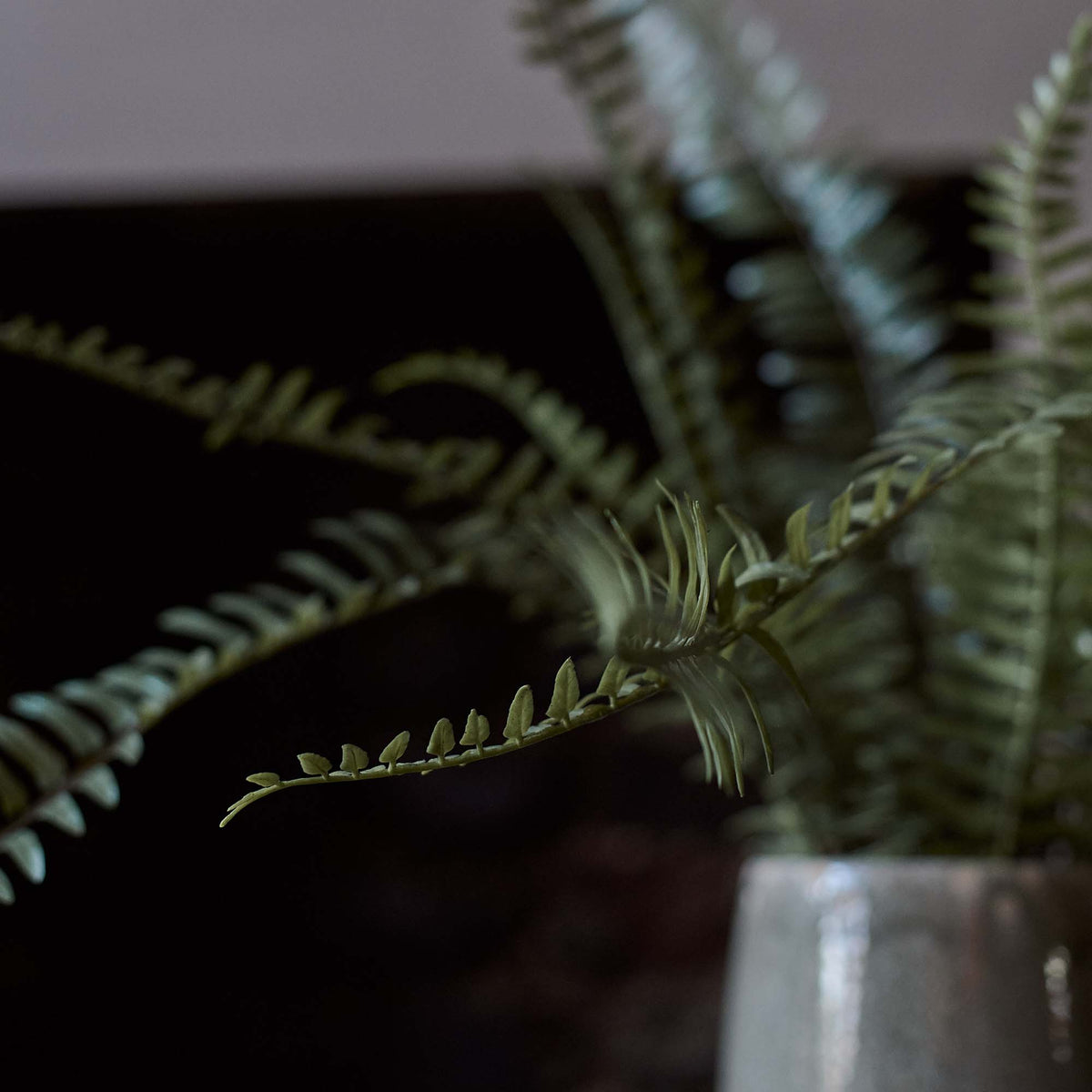 A closeup of the tall green leaves of the Artificial Fern in Khaki Pot.