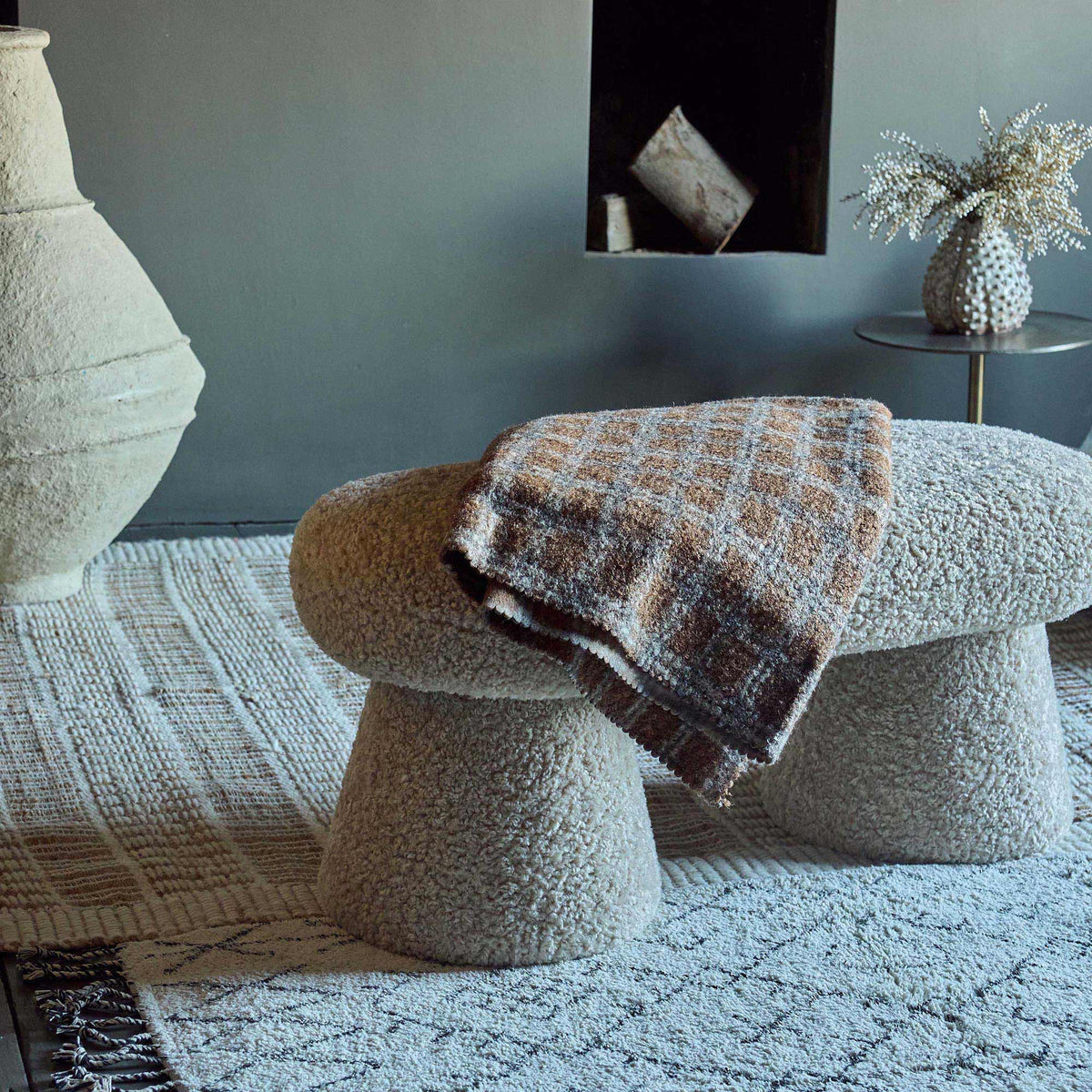 Beige boucle bench with a curved upholstered design and soft textured teddy fabric finish. Tulip boucle bench by Abigail Ahern, a luxury modern seating piece perfect for bedrooms, hallways, living rooms and contemporary interiors. Elegant accent furniture designed to add warmth, comfort and sophisticated style to modern home decor.