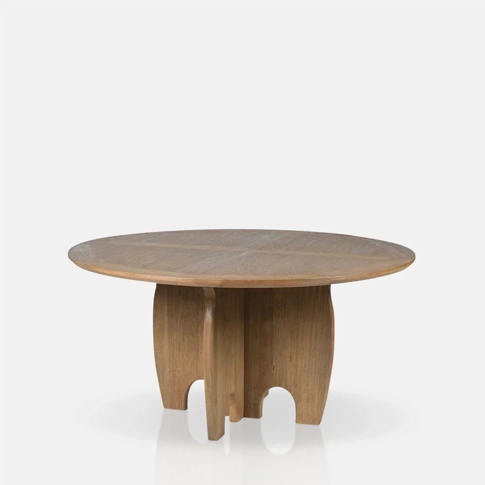 Harrington Wooden Dining Table has a round natural wood top and sculptural central pedestal formed from curved panels, shown from a slightly angled viewpoint.